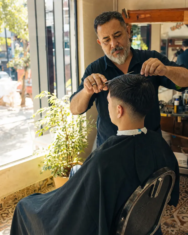 Barbero corta el pelo a un cliente joven
