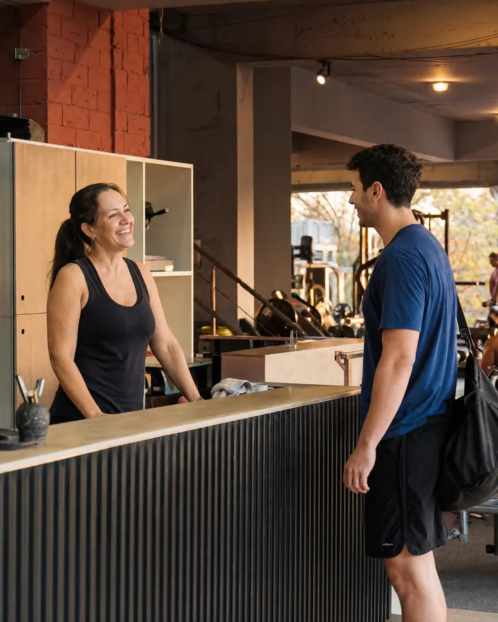 Recepcionista de un gimnasio saluda a un socio que llega