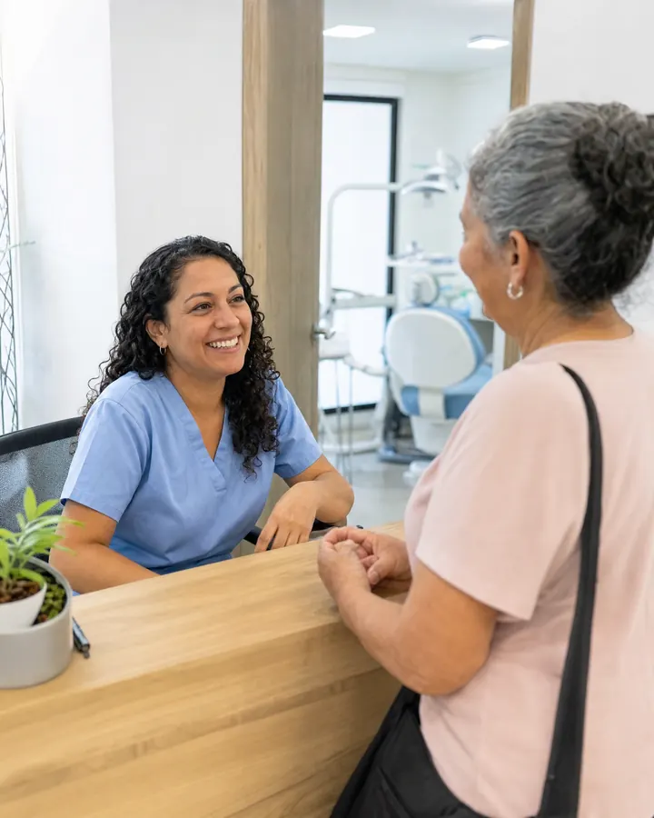 Recepcionista de un consultorio odontológico conversa con una paciente